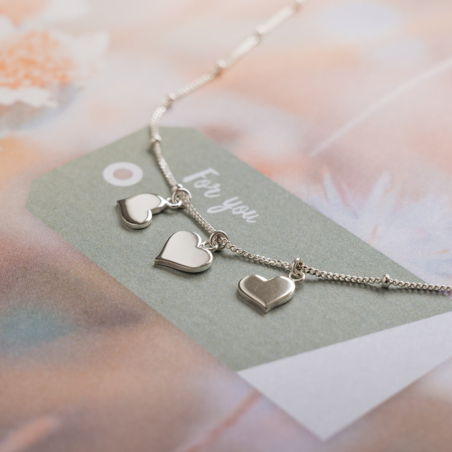 Silver three heart necklace on paper