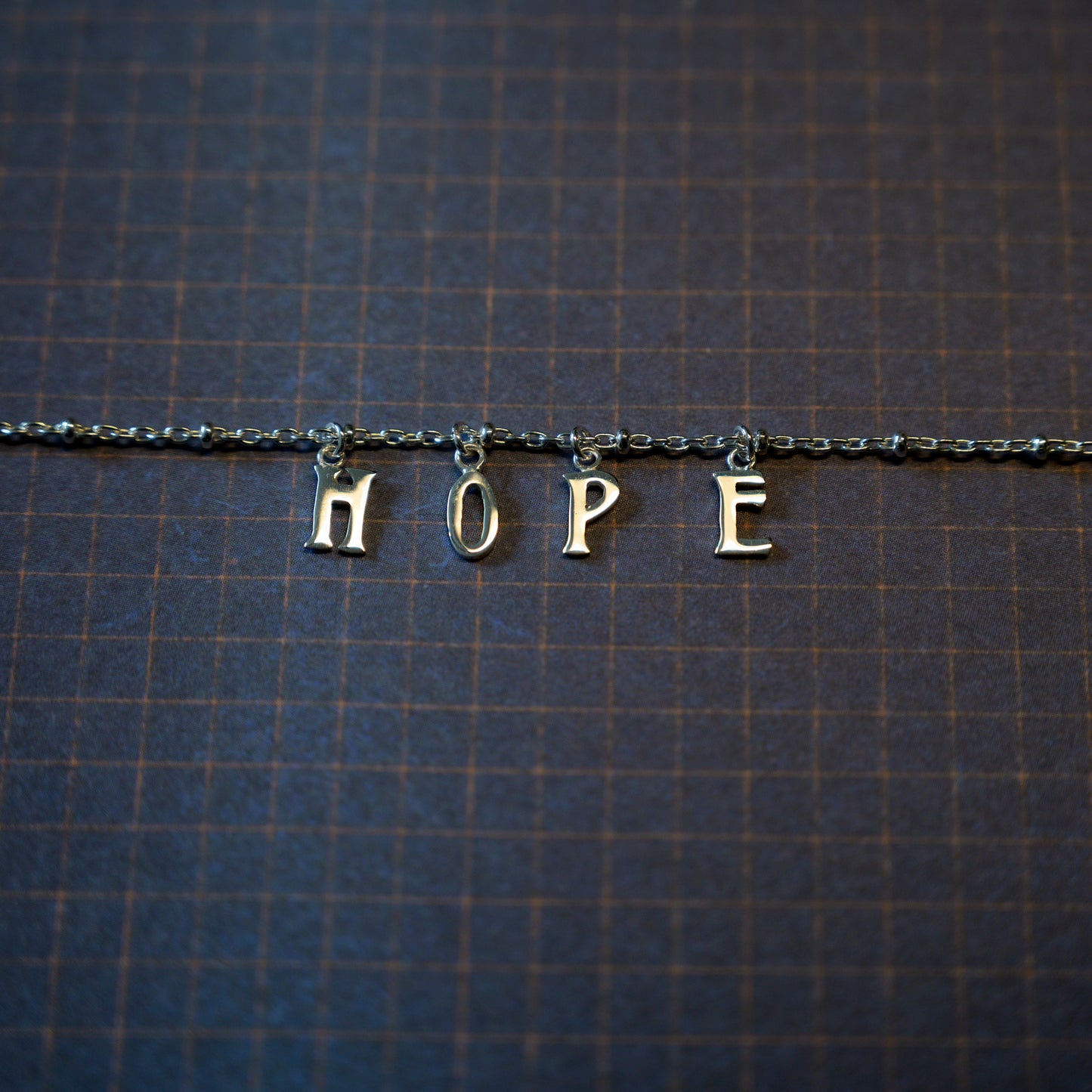 Silver hope bracelet on dark blue background