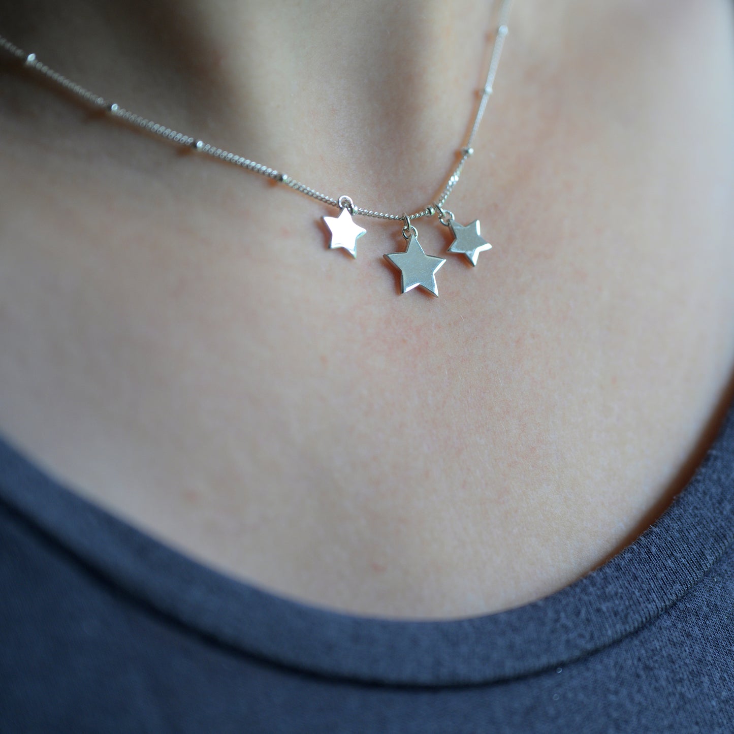 Silver three star necklace on model
