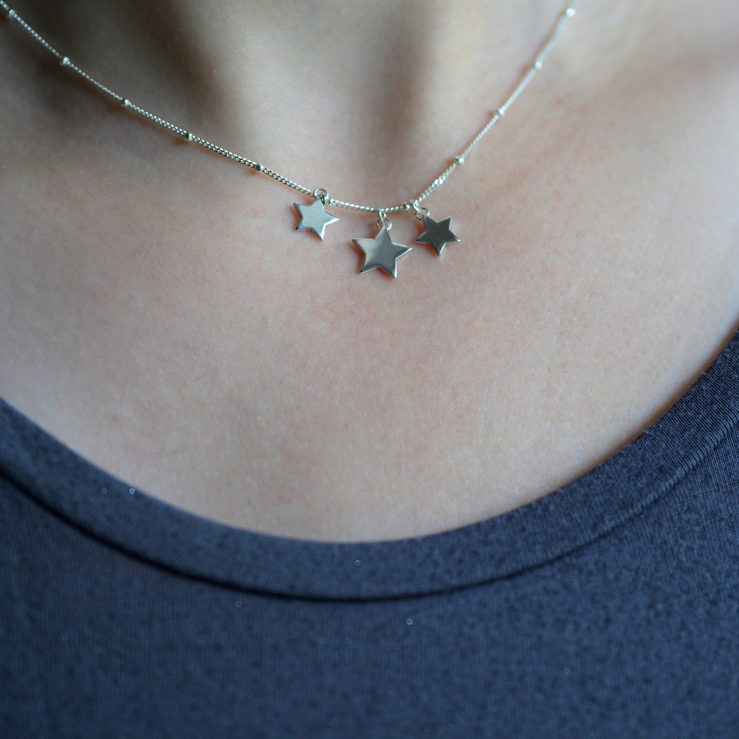 Silver three star necklace on model