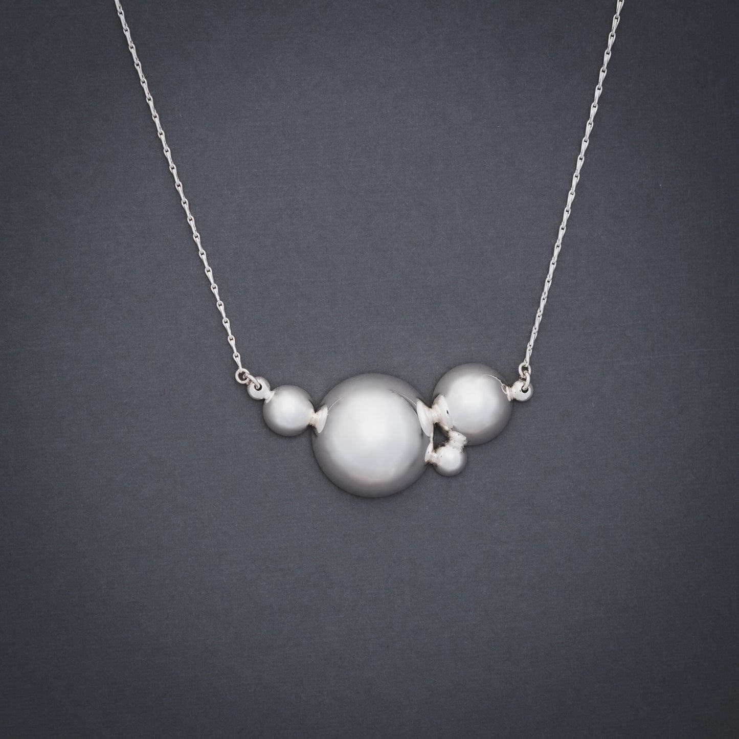 Product shot of silver necklace with six domes