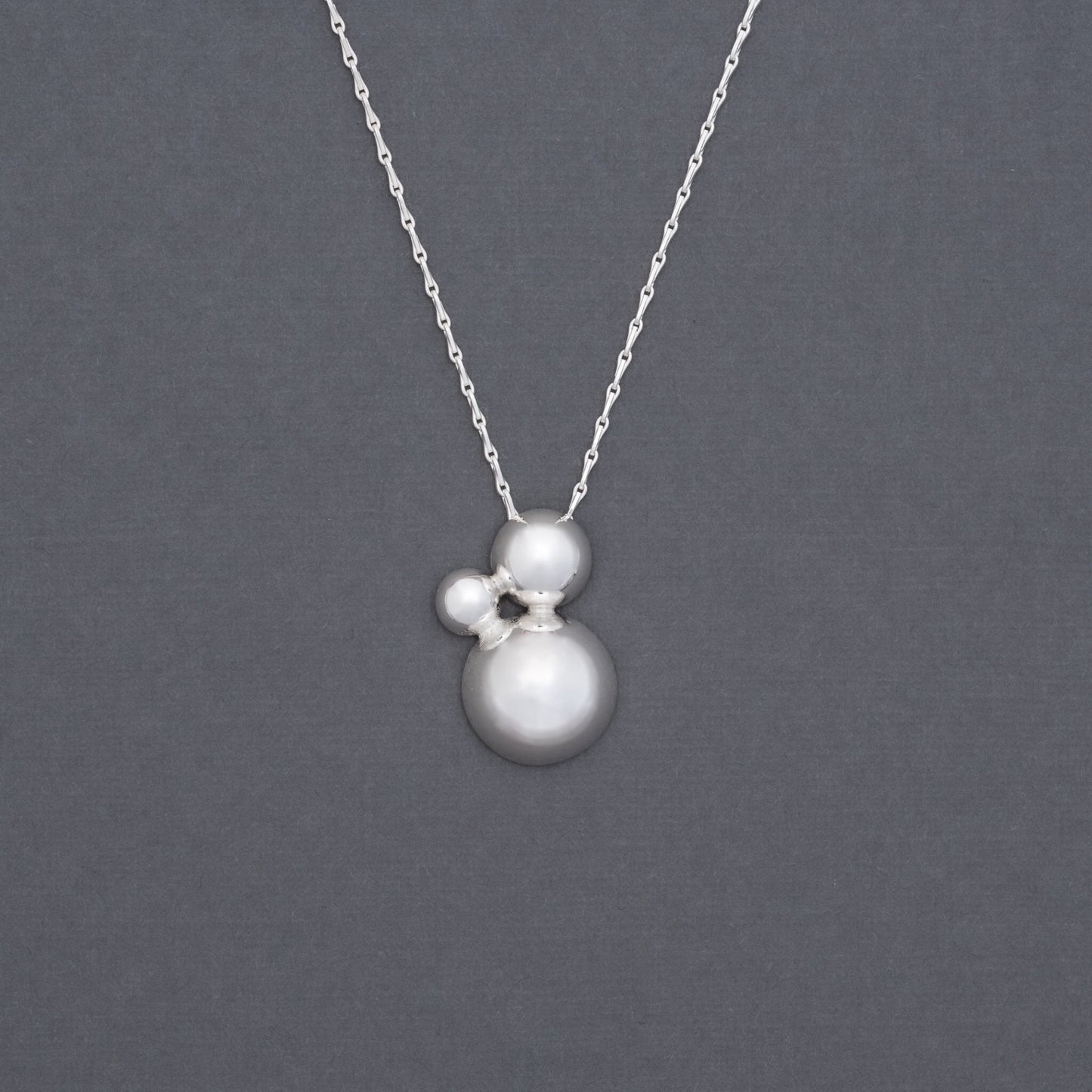 Product shot of silver pendant with three domes