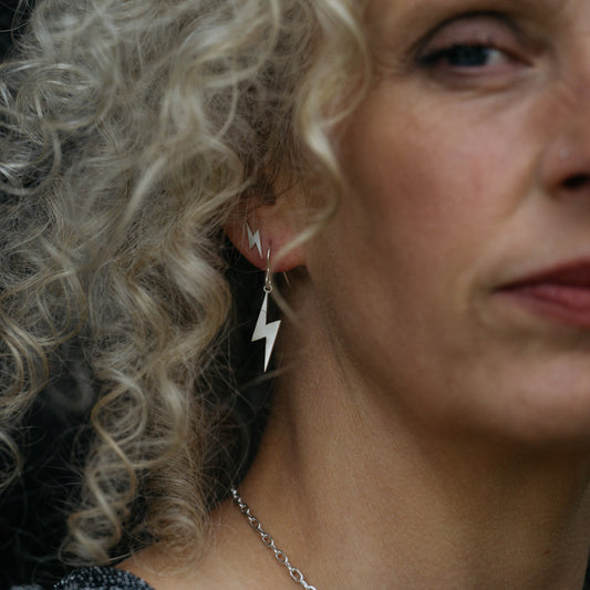 Close up of model wearing lightning studs and drop earrings