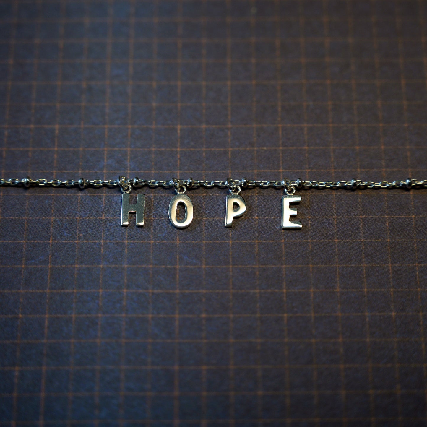 Silver hope bracelet on dark blue background