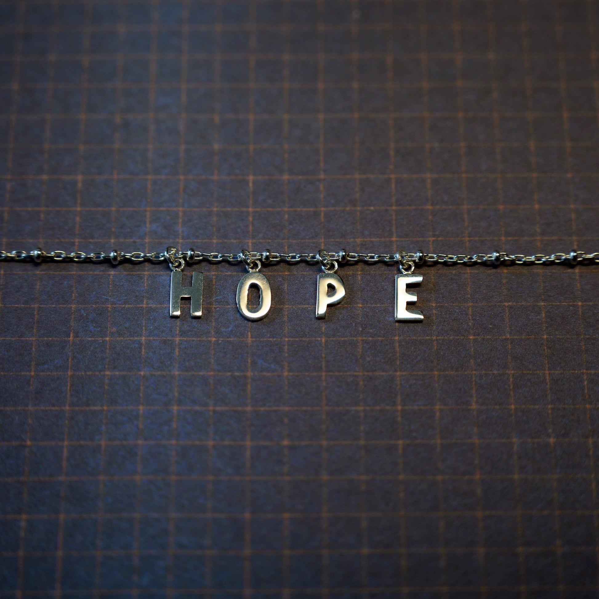 Silver hope bracelet on dark blue background
