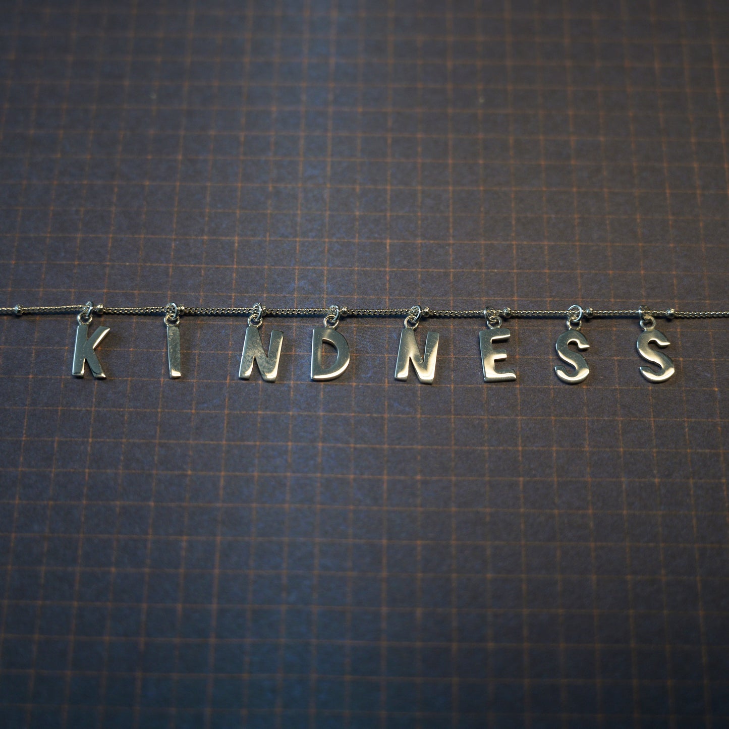 Silver Kindness necklace on dark blue background