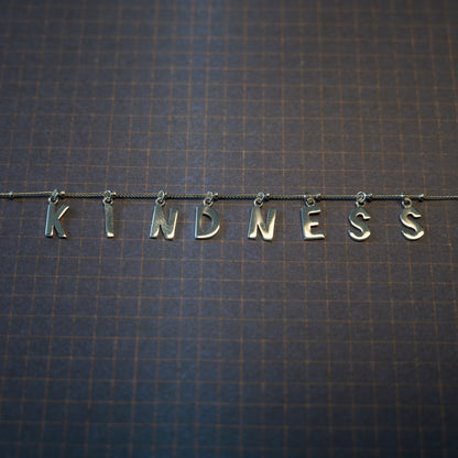 Silver Kindness necklace on dark blue background