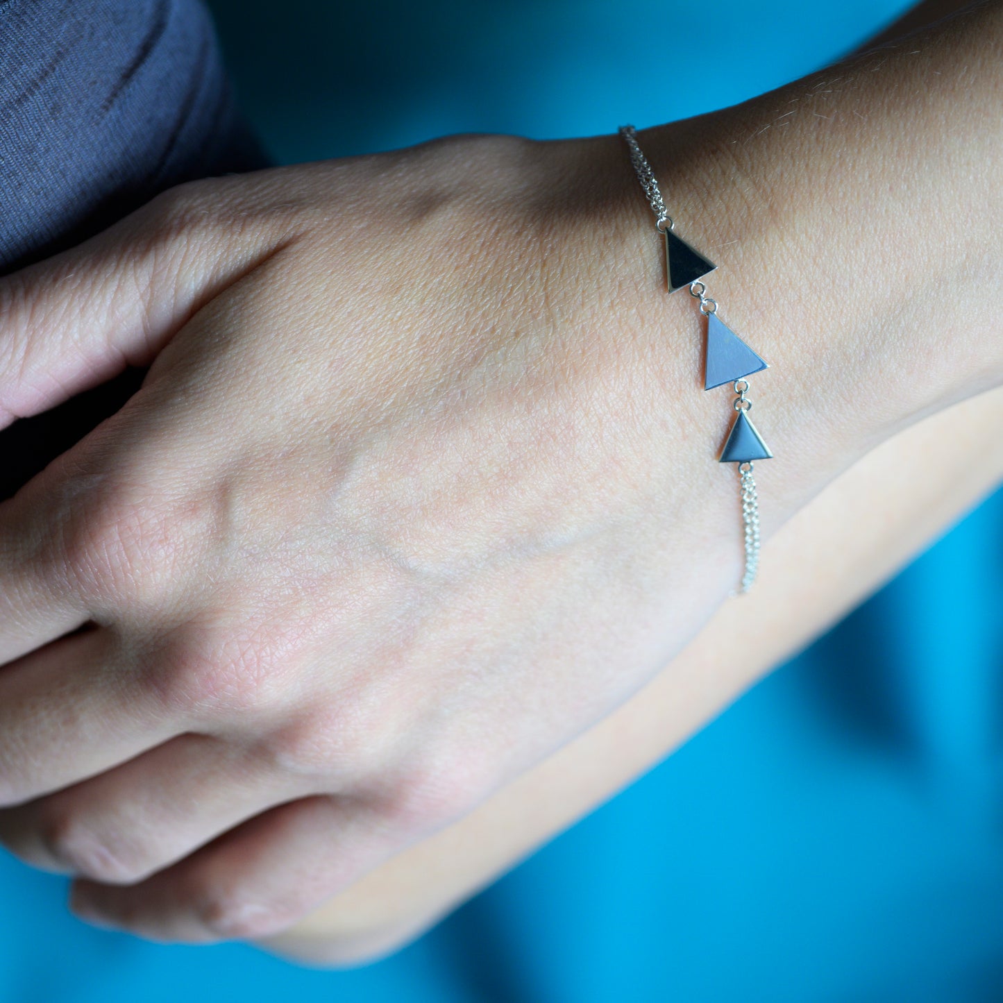 Silver bracelet with three triangles on model's wrist