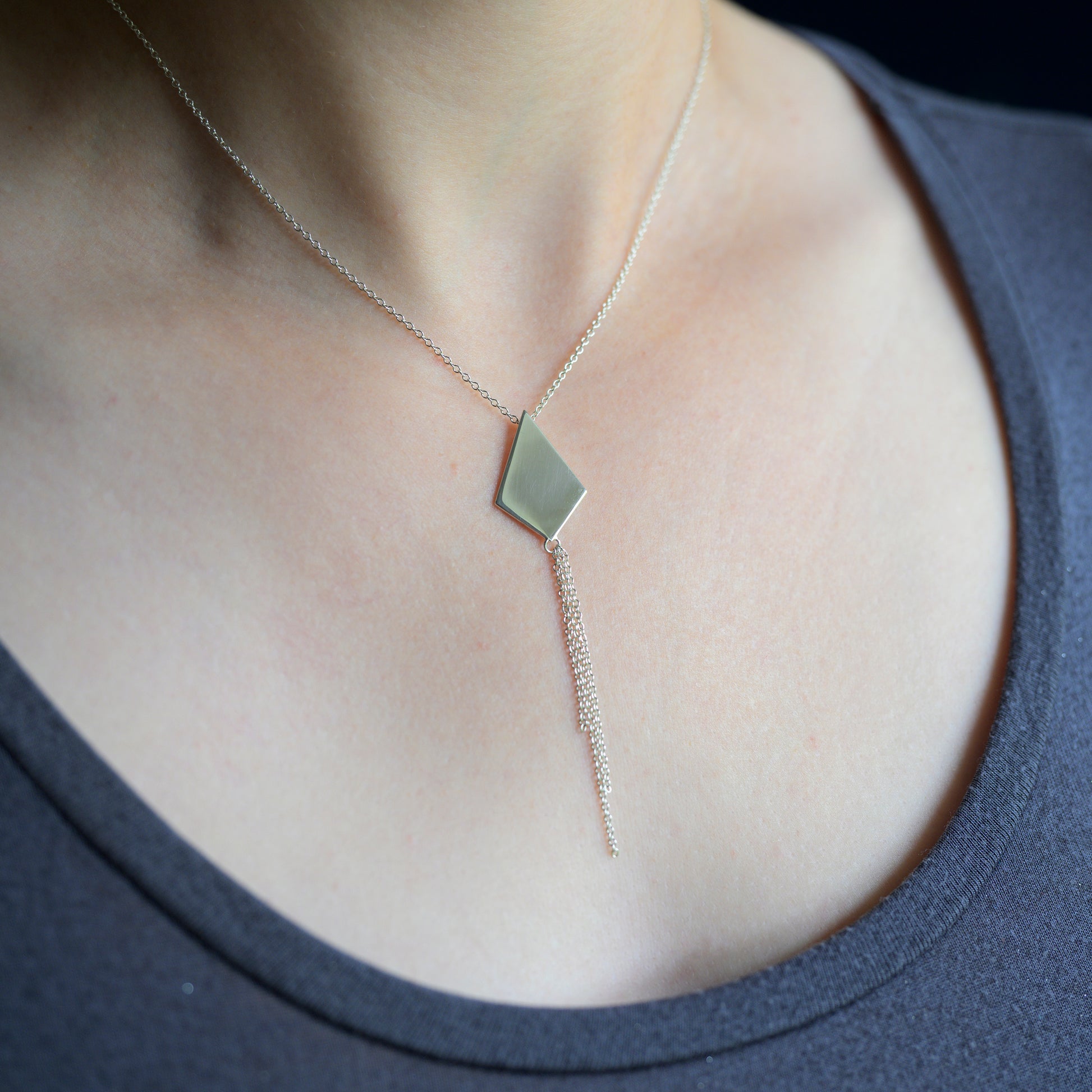 Silver kite shaped necklace with chain tassel on model