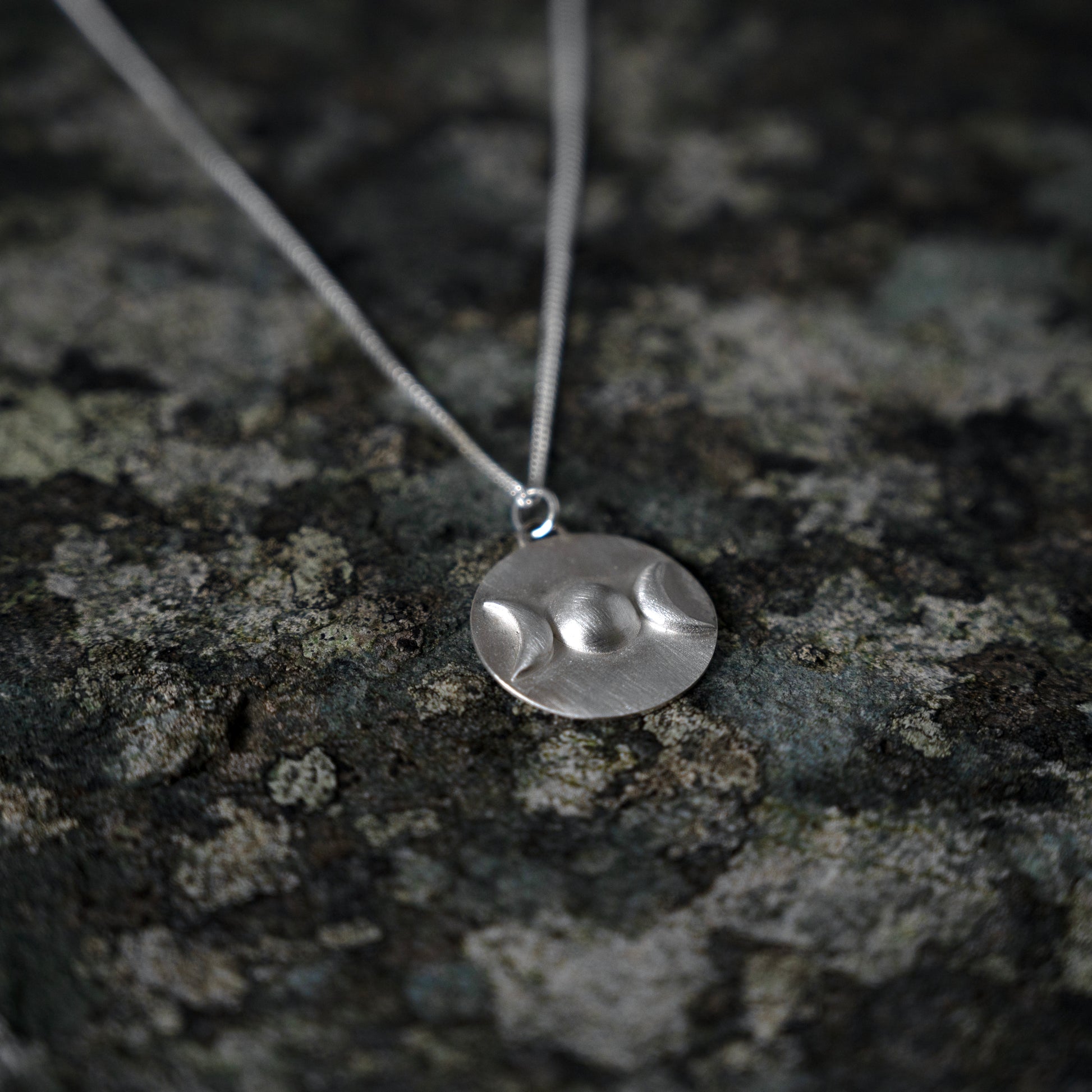 Silver pendant with triple goddess symbol, on slate background