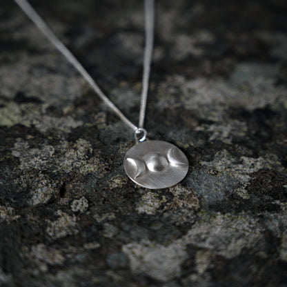 Silver pendant with triple goddess symbol, on slate background