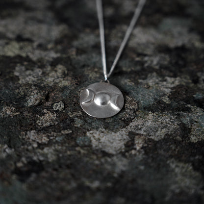 Silver pendant with triple goddess symbol, on slate background