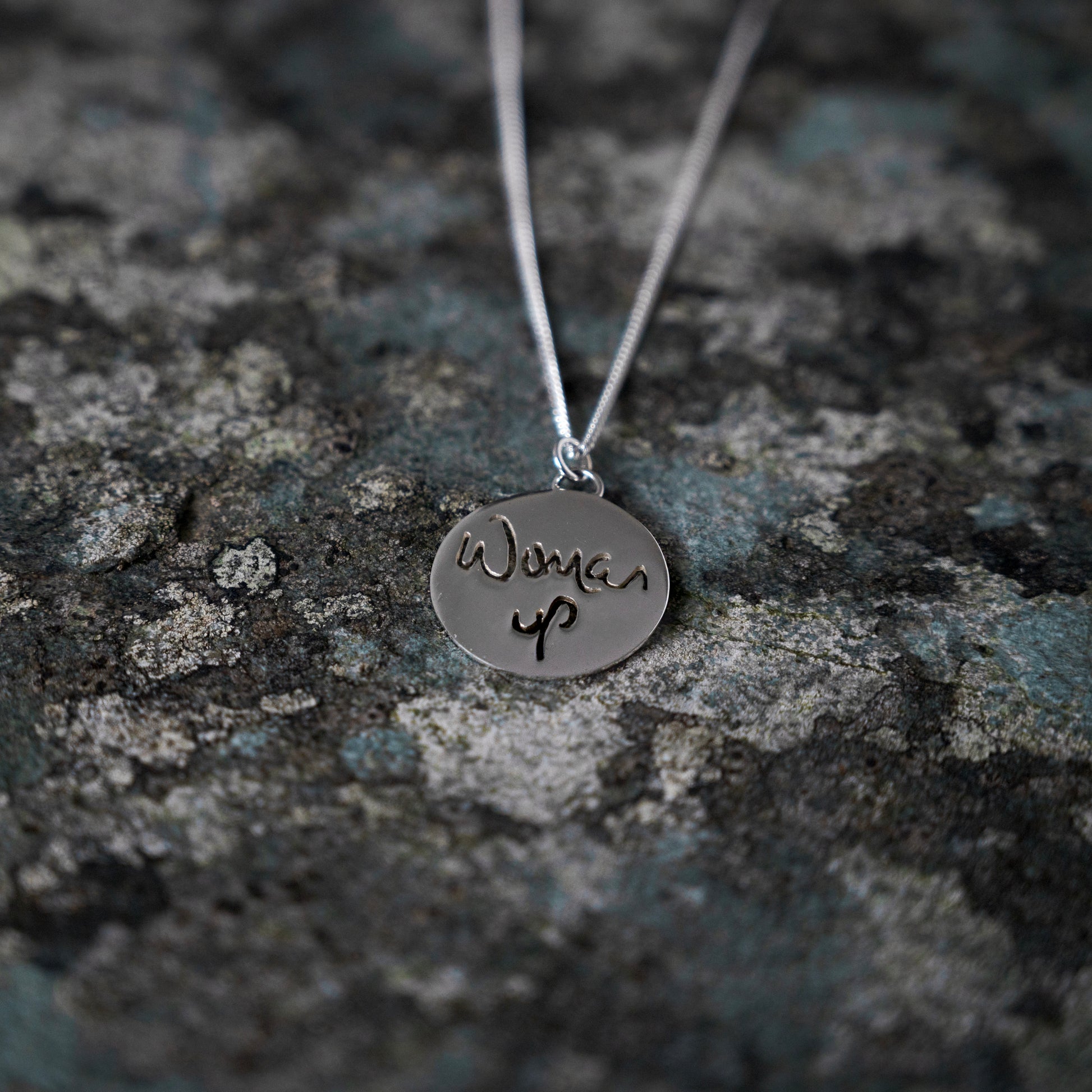 Silver pendant with woman up cut out, on slate background