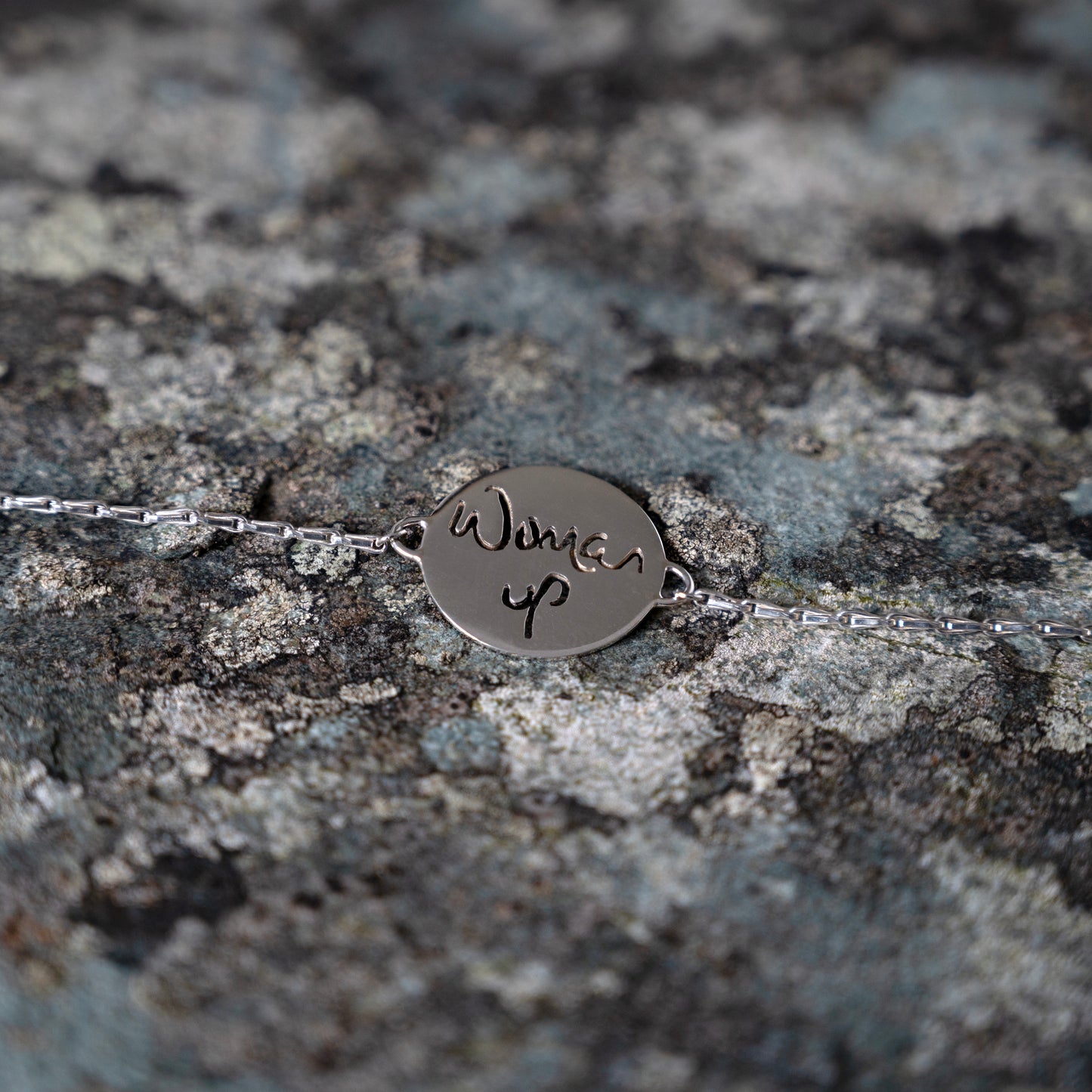 Silver bracelet with woman up cut out, on slate background