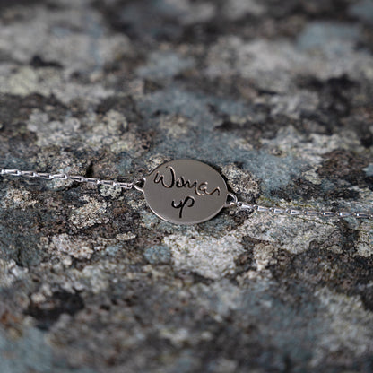 Silver bracelet with woman up cut out, on slate background