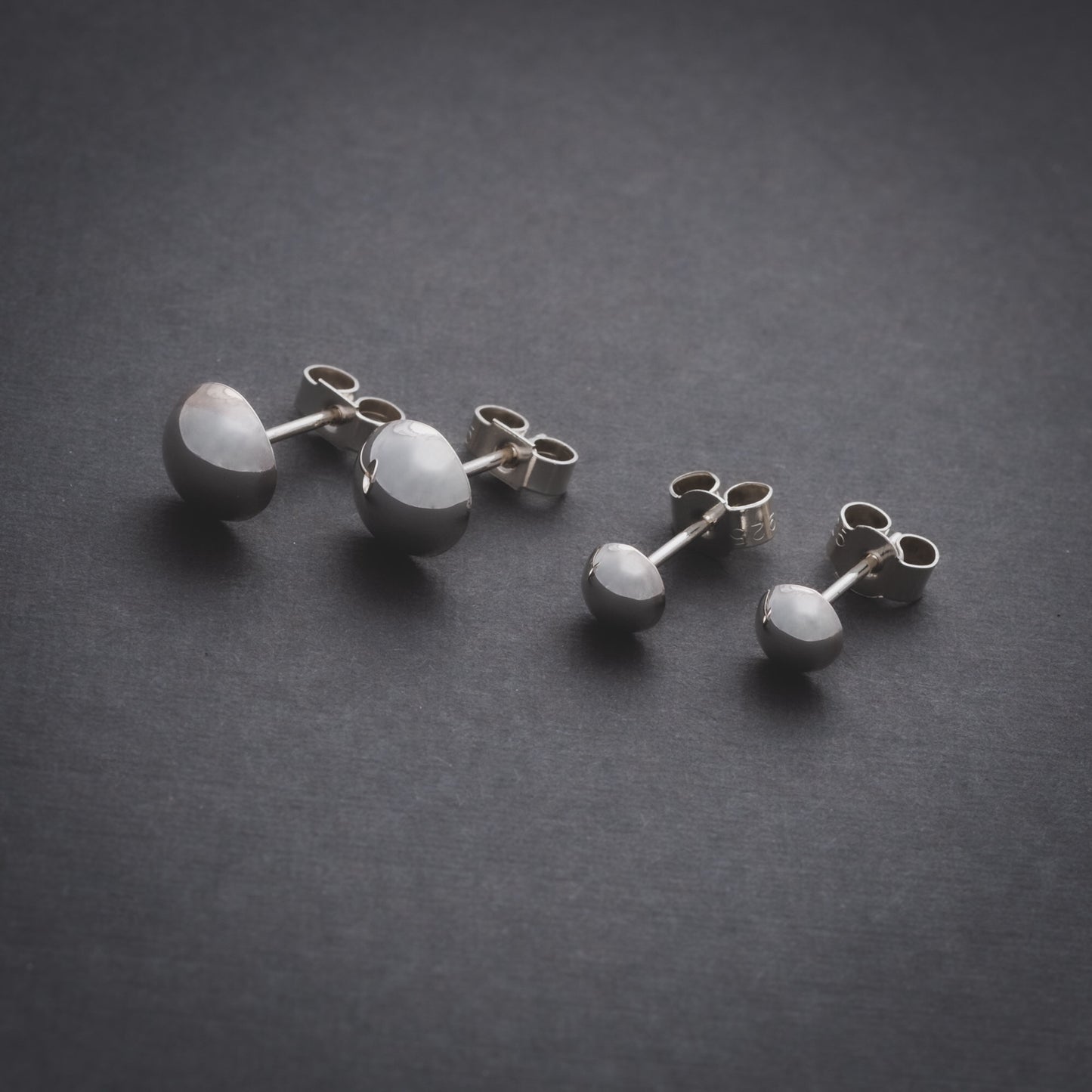 Product shot of two sizes of silver domed stud earrings